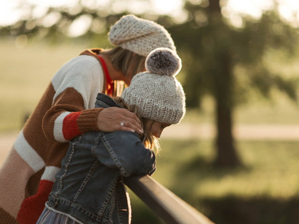 b.e.happe mommy and daughter looking over bridge with matching b.e.happe neutral pom hat and slouch hat