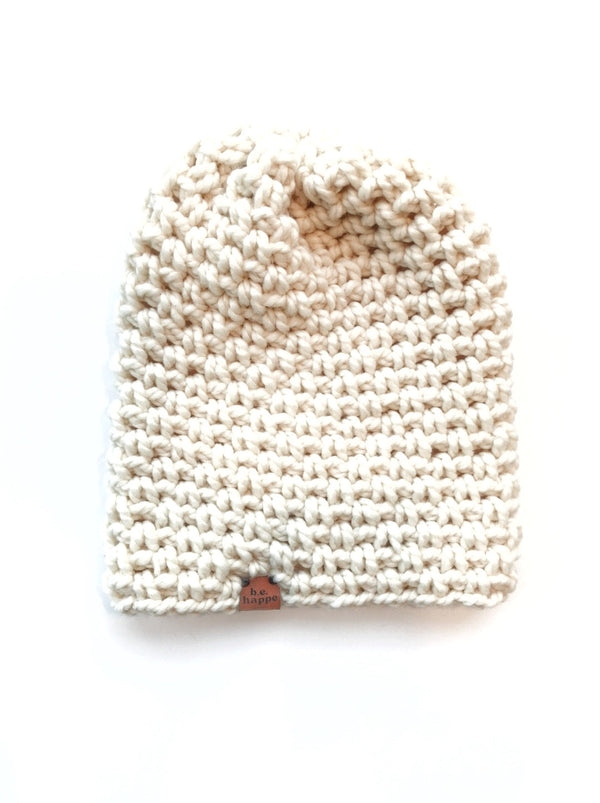 A beige, simple slouch beanie hat made from a blend of acrylic and wool, displayed on a plain background.