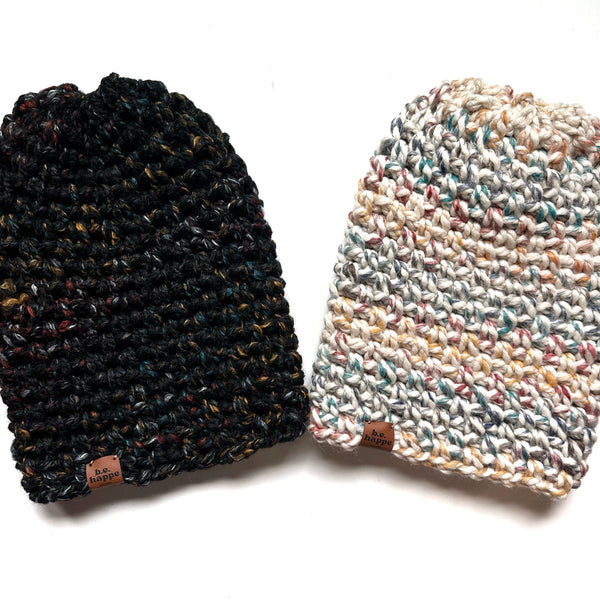 Two knitted hats, one black and one multicolored, on a white background.