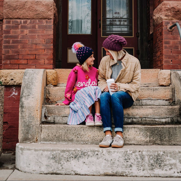 Mom and daughter sitting on steps wearing behappe branded Mommy and Me Matching Hat Sets, 