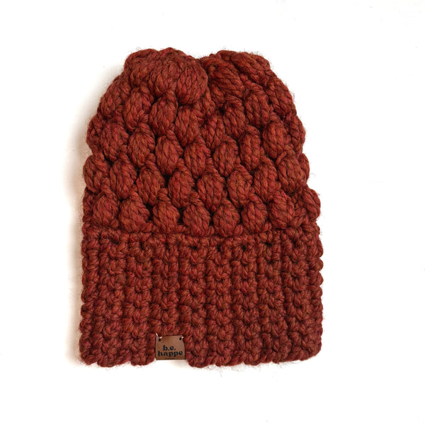 orange knitted beanie with a brand tag on a white background