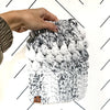 A hand holding a gray and black marbled crochet slouch hat.