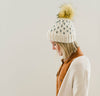 b.e.happe adult womens knit hat with faux fur pom pom; womens off white winter hat; womens knit heart hat; woman wearing winter hat with faux fur pom pom on top; adult winter beanie with heart designs; mini heart winter hat with pom pom; profile view of winter beanie with faux fur pom pom on top; winter toboggan with pom pom